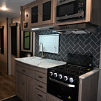 Close Up of Kitchen - Microwave Above, Cooktop and Stove, and Faucet with Storage Cabinets Above and Below
 May Show Optional Features. Features and Options Subject to Change Without Notice.