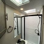 Bathroom with Shower and Skylight Above, Single Bowl Vanity with Mirror Above. Retractable shower door shown open. May Show Optional Features. Features and Options Subject to Change Without Notice.
