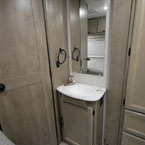 Bathroom Door Shown Closed, Next to Mirror with Single Bowl Vanity Below.
 May Show Optional Features. Features and Options Subject to Change Without Notice.