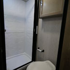 Shower with White Shower Surround and Skylight, Next to Toilet with Medicine Cabinet Overhead.
 May Show Optional Features. Features and Options Subject to Change Without Notice.