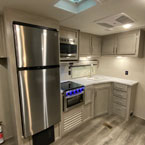 Kitchen Galley with Stainless Steel Refrigerator, Microwave Overhead of Stove/Oven, Cabinets Overhead and Below Sink.
 May Show Optional Features. Features and Options Subject to Change Without Notice.