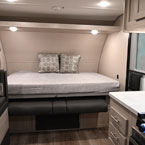 Part of Dinette and Kitchen Area Shown. Murphy Bed Shown in the Open Position with Two Decorative Pillows. Shelf Above Bed with Two Push Lights.
 May Show Optional Features. Features and Options Subject to Change Without Notice.
