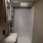 Bathroom- Shower with White Surround and Skylight. Mirrored Medicine Cabinet with Single Bowl Vanity Below.
 May Show Optional Features. Features and Options Subject to Change Without Notice.
