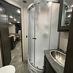 Bathroom from bedroom door, One Piece ABS Shower Surround, Retractable Shower Door, Porcelain Toilet with Foot Flush, Stainless Lavatory Sink with mirror and cabinet
 May Show Optional Features. Features and Options Subject to Change Without Notice.