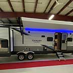 Exterior view of Coachmen Catalina Legacy Edition 323QBTSCK with awning out and Multicolor LED Strip lights and outside kitchen
 May Show Optional Features. Features and Options Subject to Change Without Notice.